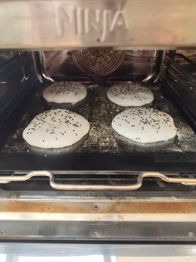 Vier Ciabatta-Burgerbrötchen auf dem Schülback-Backstahl im Ninja Woodfire Outdoor Ofen