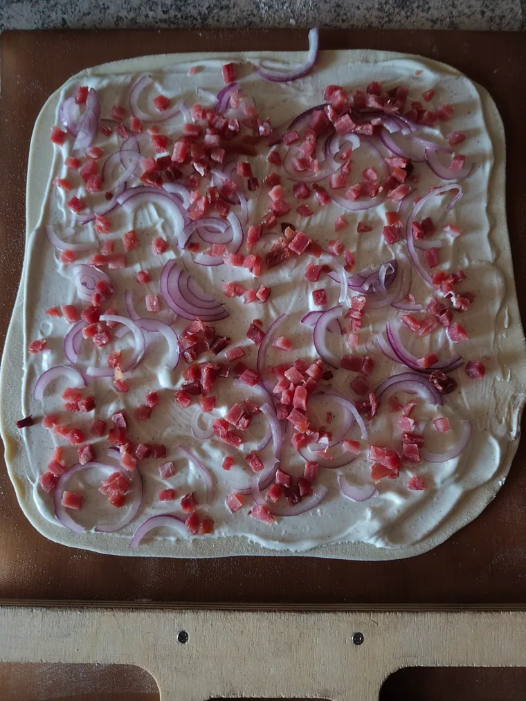 Ungebackener Flammkuchen mit Schmand, Schinkenwürfeln und roten Zwiebeln