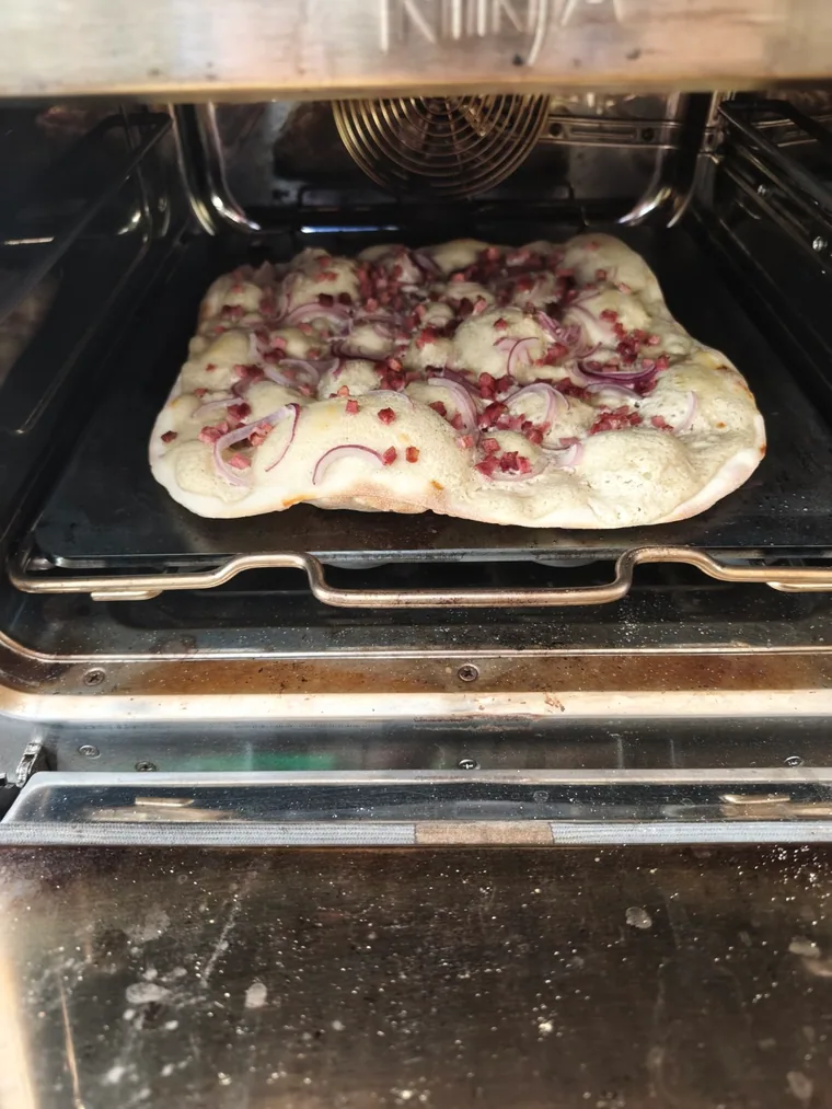 Flammkuchen mit kräftigen Teigblasen auf dem Schülback-Backstahl im Ofen